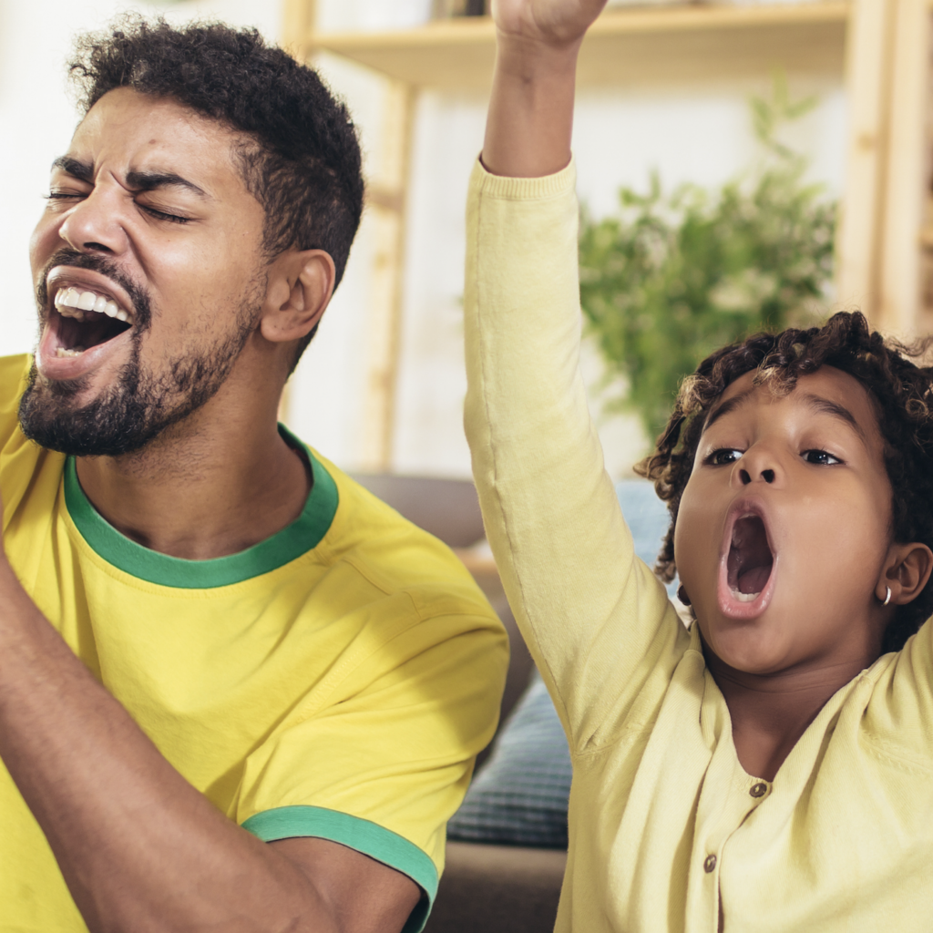 A man and a child in yellow shirts cheering excitedly.