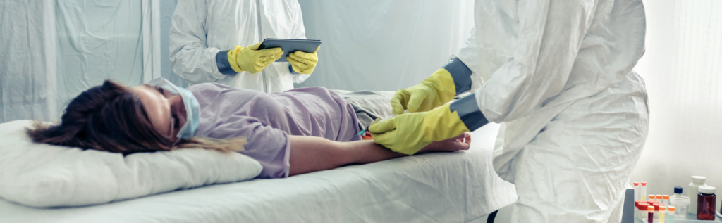 Healthcare professionals in protective suits examining a patient in a medical facility.