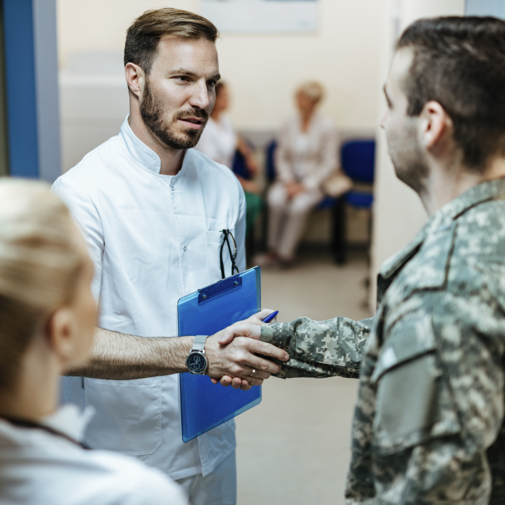 Doctor in a white coat shaking hands with a military service member in uniform.