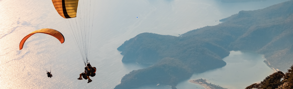 Two paragliders soaring over a scenic landscape.