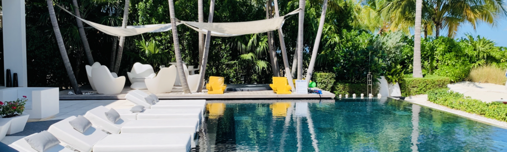 Luxurious villa pool area with sun loungers, hammock, and tropical plants.